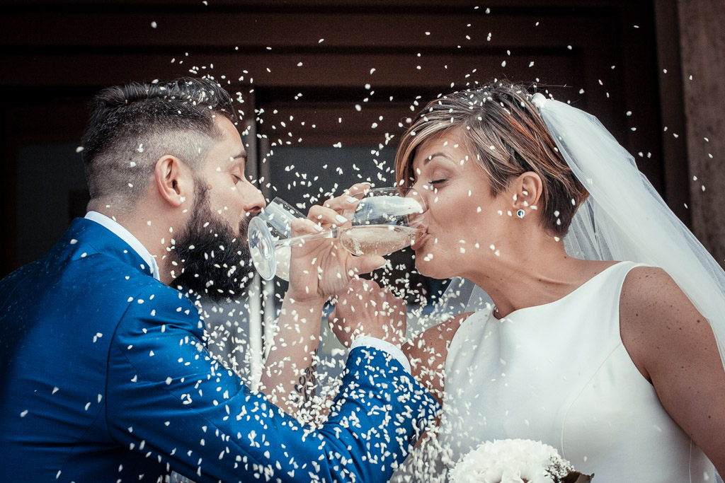 lacio del riso agli sposi dopo la cerimonia di matrimonio mentre brindano davanti alla chiesa di palù di zevio